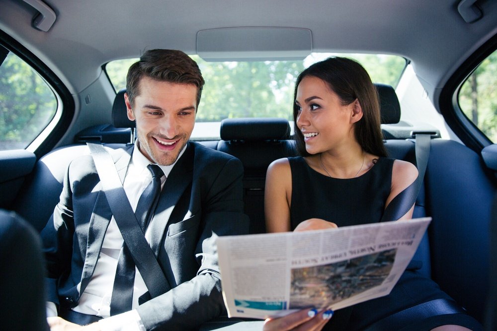 Happy couple reading newspaper in car.jpeg